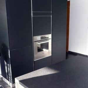 Une belle armoire noire, sans poignées qui donne du cachet à la pièce. cuisine sans poignées