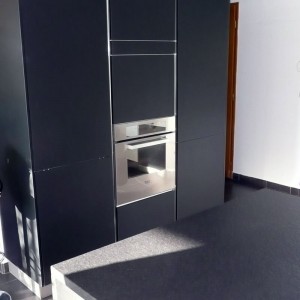 Une belle armoire noire, sans poignées qui donne du cachet à la pièce. cuisine sans poignées